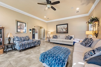 Tiled living room featuring crown molding, arched walkways, recessed lighting, and a ceiling fan