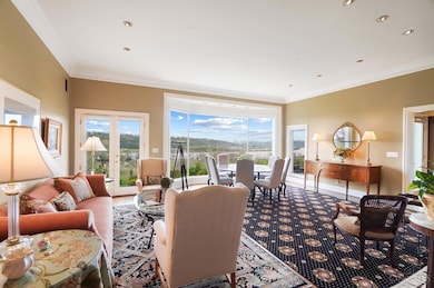 The bright, spacious and inviting great room boasts an 11' ceiling with recessed lighting, a wall of bowed floor-to-ceiling windows showcasing the picturesque river view, walkout access to the rear terrace, a gas fireplace and gleaming hardwood floors.