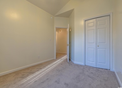 Unfurnished bedroom with lofted ceiling, carpet flooring, and a closet