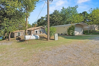 View of front of property with a front lawn, a carport, a detached garage, and an outdoor structure