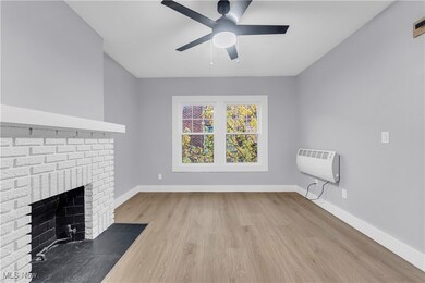 Unfurnished living room featuring light wood-style floors, heating unit, a fireplace, and ceiling fan
