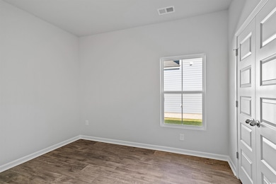 Empty room featuring baseboards and dark wood-style flooring