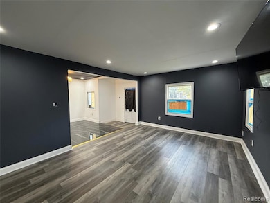 Empty room featuring dark wood-type flooring and recessed lighting