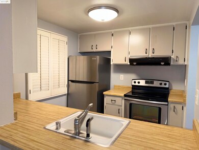 Kitchen featuring appliances with stainless steel finishes, light countertops, and under cabinet range hood