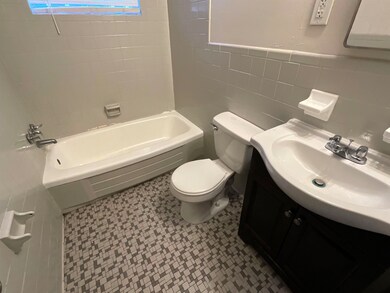 Full bathroom with tile walls, toilet, vanity, and tiled shower / bath