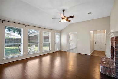 Unfurnished living room featuring vaulted ceiling, dark wood finished floors, ceiling fan, and a brick fireplace