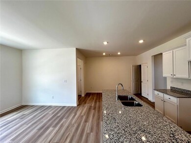 Kitchen featuring wood finished floors, recessed lighting, dark stone counters, and white cabinetry