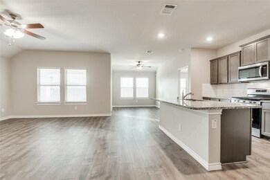 Kitchen featuring ceiling fan, stainless steel appliances, backsplash, dark brown cabinets, and a center island with sink