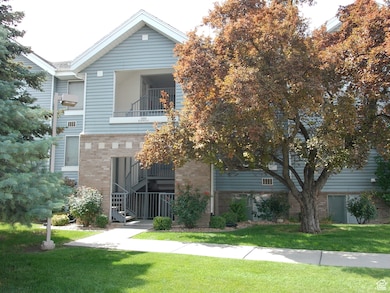 View of front of property with a balcony, brick siding, a front yard, and stairs