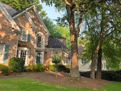 View of front of property featuring brick siding, a chimney, and a front lawn