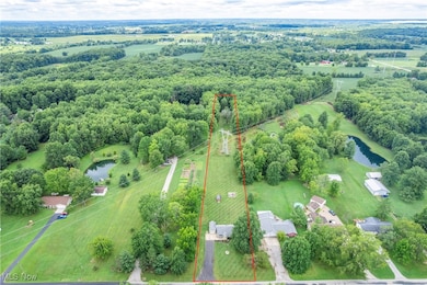 Aerial view of sparsely populated area with a nearby body of water and property parcel outlined
