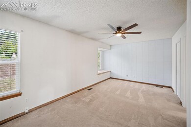 Carpeted empty room with a textured ceiling and ceiling fan