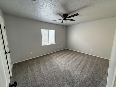 Carpeted spare room featuring a textured ceiling and a ceiling fan