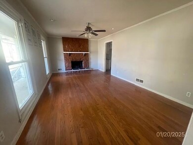 Unfurnished living room with crown molding, ceiling fan, wood finished floors, and a stone fireplace