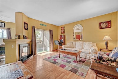 Living room featuring a fireplace, wood finished floors, and a healthy amount of sunlight