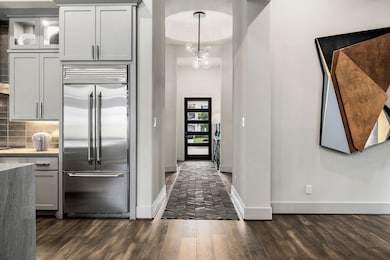 Welcome guests into a beautiful corridor with soaring ceilings, custom designer paint, and beautiful wood floors, all bathed in the warm glow of an elegant chandelier from Italy.