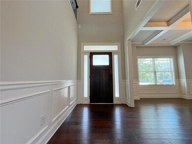 Foyer featuring a decorative wall, dark wood-type flooring, a wainscoted wall, beamed ceiling, and coffered ceiling