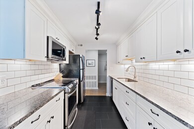 Kitchen with stainless steel appliances, white cabinets, and stone countertops