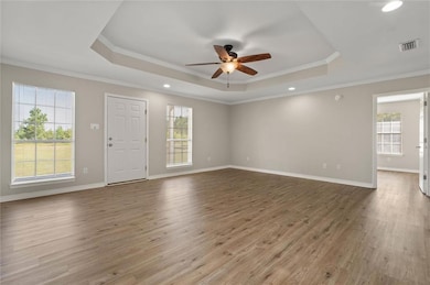 Living room featuring a tray ceiling, ceiling fan, plenty of natural light, wood finished floors, and crown molding