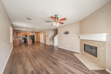 Unfurnished living room with a ceiling fan, a tile fireplace, arched walkways, dark wood-type flooring, and stairway