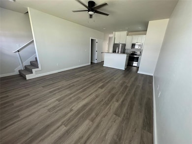 Unfurnished living room featuring a ceiling fan, d