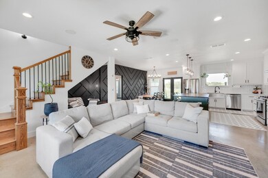 Living room with french doors, sink, and ceiling fan with notable chandelier