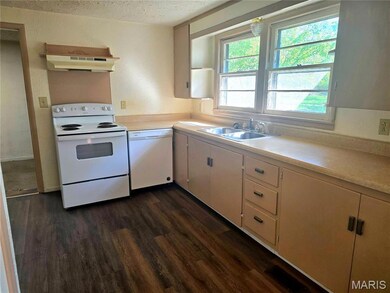 Kitchen featuring white appliances, light countertops, dark wood-type flooring, under cabinet range hood, and white cabinets