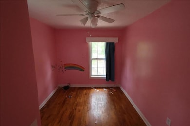 Unfurnished room featuring baseboards, wood finished floors, and ceiling fan