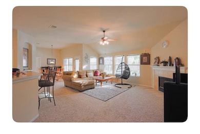 Living area with light carpet, a ceiling fan, a t