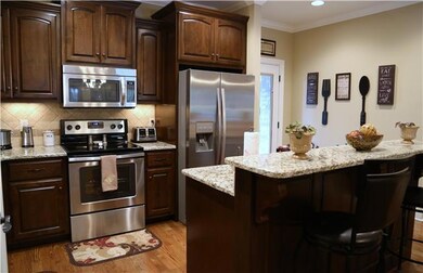 This stunning kitchen with granite, tumbled stone backsplash, stainless appliances, bar and open living space, great to entertain
