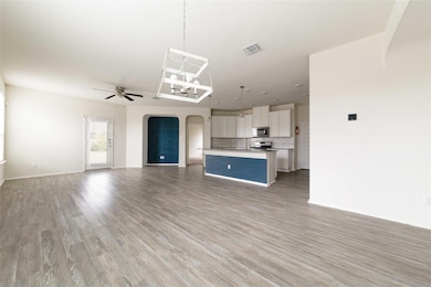 Unfurnished living room featuring ceiling fan, li