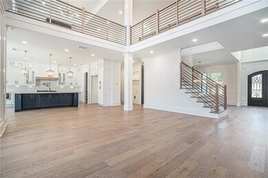 Unfurnished living room with light wood-type flooring, stairs, a towering ceiling, decorative columns, and recessed lighting