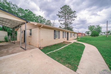 View of front facade featuring a carport, brick siding, and a front yard