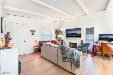 Living area with beam ceiling, light wood finished floors, a fireplace, and a textured ceiling