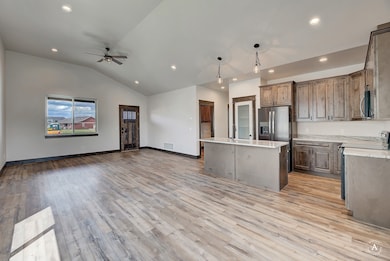 Kitchen with open floor plan, pendant lighting, appliances with stainless steel finishes, recessed lighting, and a kitchen island with sink
