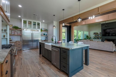 Kitchen featuring open shelves, a breakfast bar, glass insert cabinets, hanging light fixtures, and premium appliances