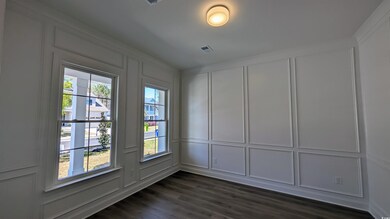 Spare room with a decorative wall, dark wood finished floors, and visible vents