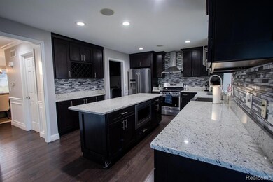 Kitchen featuring dark cabinetry, stainless steel appliances, tasteful backsplash, and recessed lighting