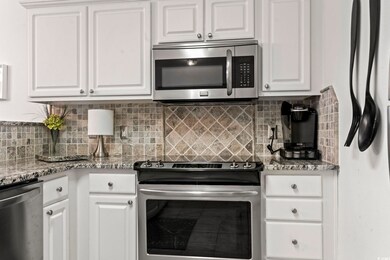 Kitchen with light stone countertops, white cabine