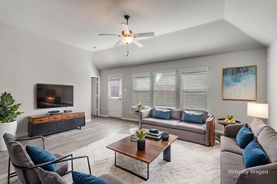 Living area with vaulted ceiling, light wood finished floors, and a ceiling fan