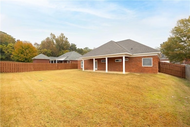 Back of house with a shingled roof, brick siding, a fenced backyard, and a patio area