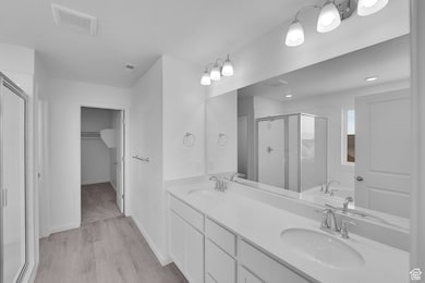 Full bath with a stall shower, a bath, double vanity, light wood-type flooring, and a walk in closet
