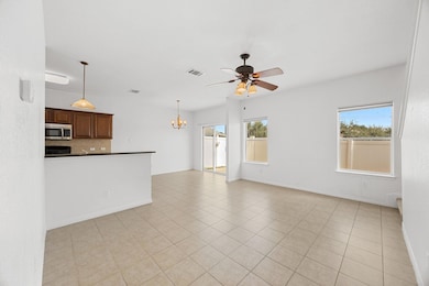 Unfurnished living room with light tile patterned floors, a chandelier, and a ceiling fan