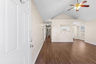 Unfurnished living room with dark wood finished floors, vaulted ceiling, and ceiling fan