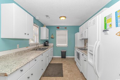 Kitchen with sink, white appliances, light tile pa