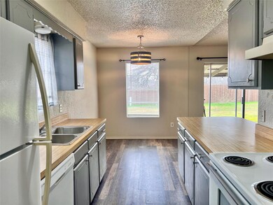 Kitchen with pendant lighting, white appliances, gray cabinetry, dark hardwood / wood-style floors, and a textured ceiling