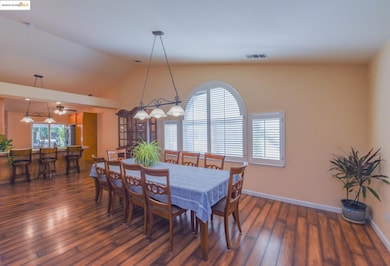 Dining space featuring dark wood-style flooring and high vaulted ceiling