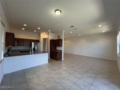 Kitchen with crown molding, open floor plan, stainless steel fridge with ice dispenser, light tile patterned floors, and recessed lighting