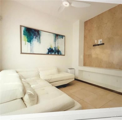 Living area featuring tile patterned floors, a ceiling fan, and baseboards