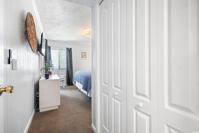 Bedroom with a textured ceiling, baseboards, and dark colored carpet